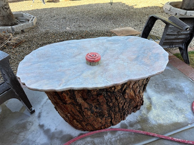Outdoor table built from a tree stump base with a leathered quartzite top